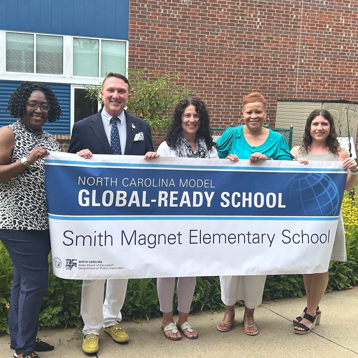  Smith Magnet Elementary staff smile while holding their Global-Ready banner